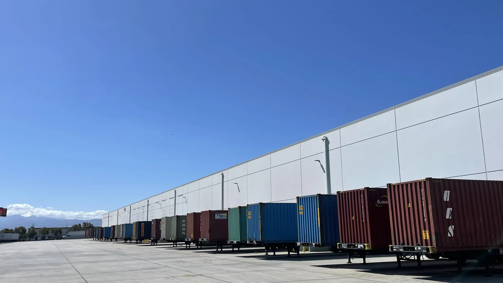 Container trailers staged beside a large warehouse